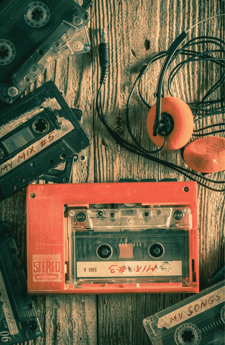 Walkman with headphones and cassette tapes on a wooden table.